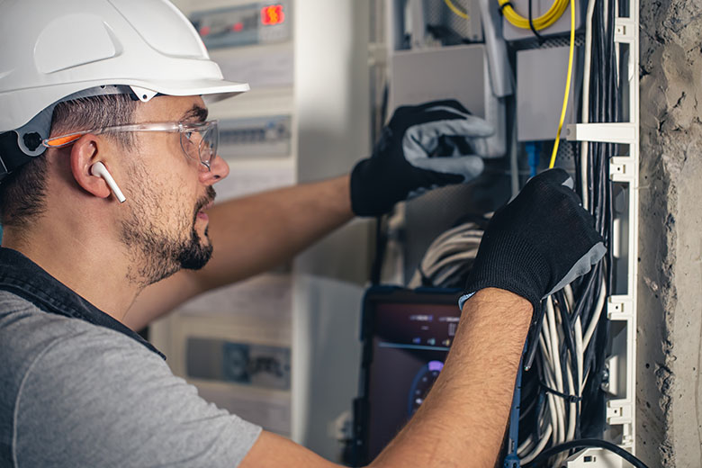 Man, an electrical technician working in a switchboard with fuses.